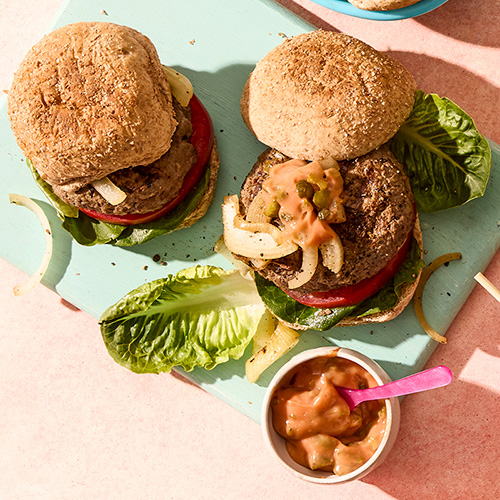 Barbecued beef burgers in toasted wholemeal rolls with lettuce, onions and burger sauce