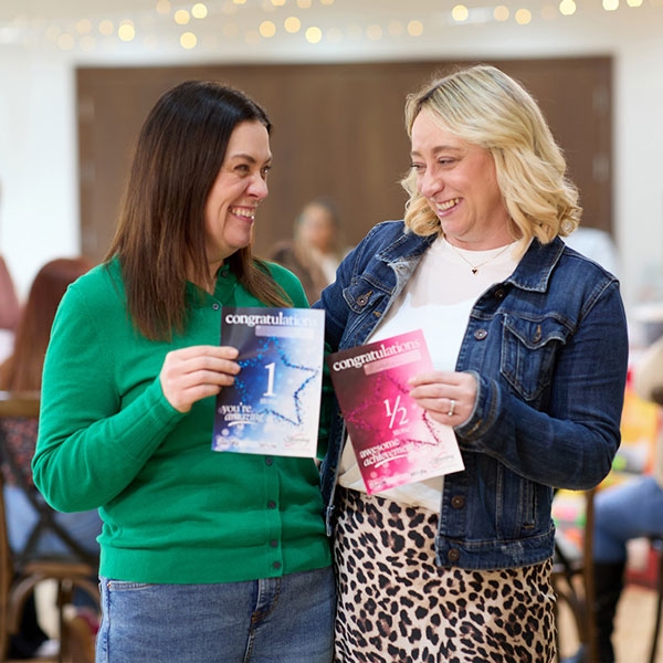 Two group members smiling and holding up their weight loss certificates